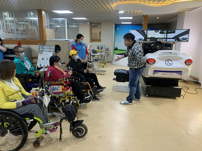 图为中心技术人员讲解残疾人模拟驾车装置